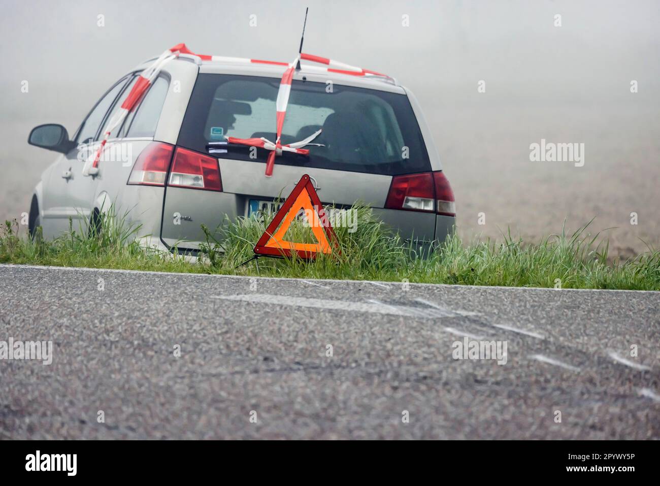 Un'auto in un prato, incidente con triangolo segnaletico, segni di slittamento indicano che il veicolo ha lasciato la strada di campagna, Rheinmuenster, Baden-Wuerttemberg Foto Stock