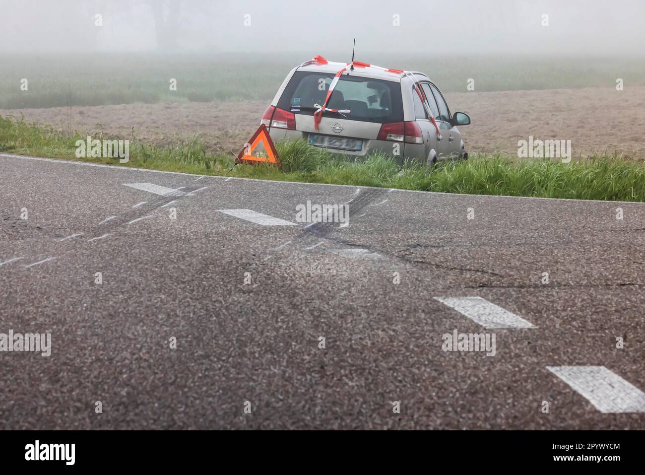 Un'auto in un prato, incidente con triangolo segnaletico, segni di slittamento indicano che il veicolo ha lasciato la strada di campagna, Rheinmuenster, Baden-Wuerttemberg Foto Stock