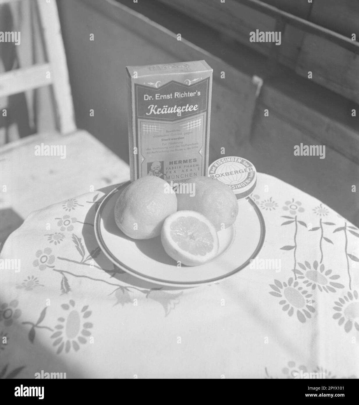 I limoni e una confezione di tisane si trovano su un piatto su un tavolo al sole. Foto Stock