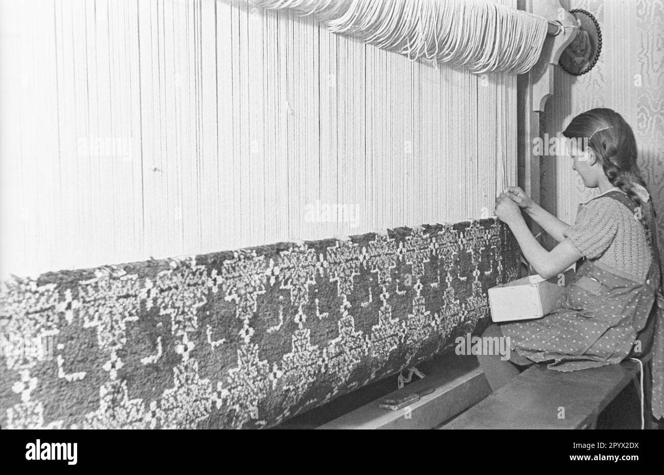 Una ragazza fa un tappeto. È probabilmente una ragazza BDM durante il suo Landfrauenjahr (anno obbligatorio di servizio delle donne in campagna). Vive e lavora in un laboratorio artigianale a Lubmin. La foto è stata scattata nella provincia di Pomerania. Foto Stock