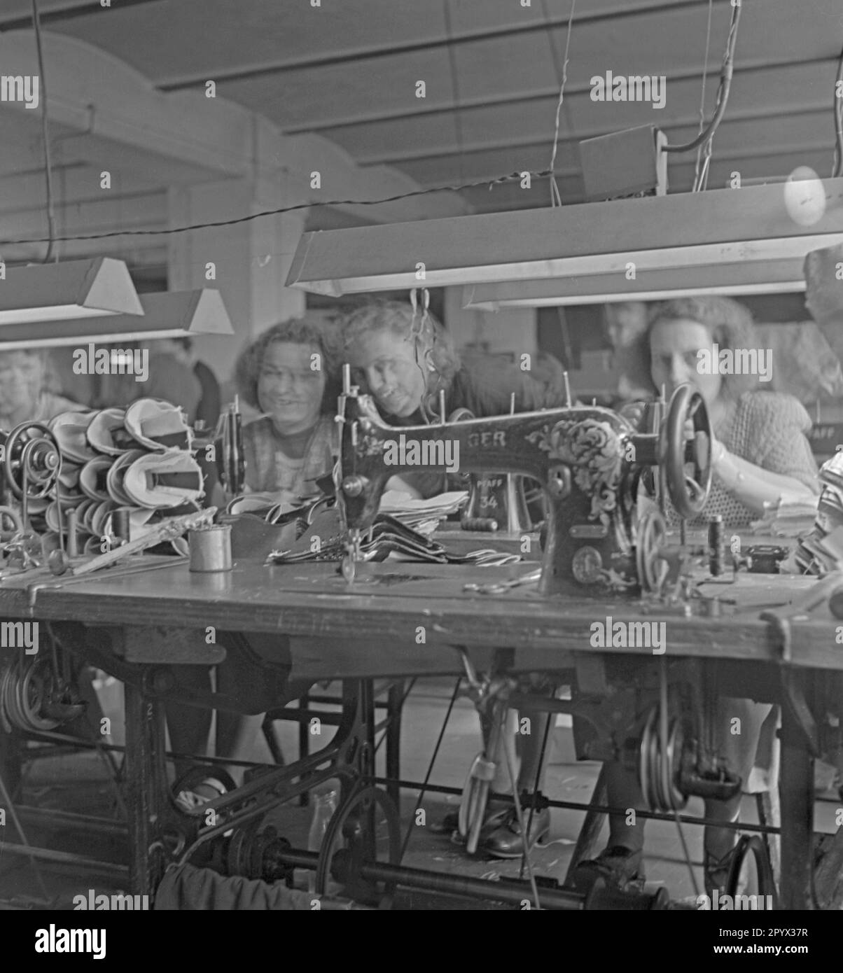 In un workshop del Fondo delle Nazioni Unite per l'infanzia a Berlino, le donne fanno scarpe su una macchina da cucire. Foto Stock