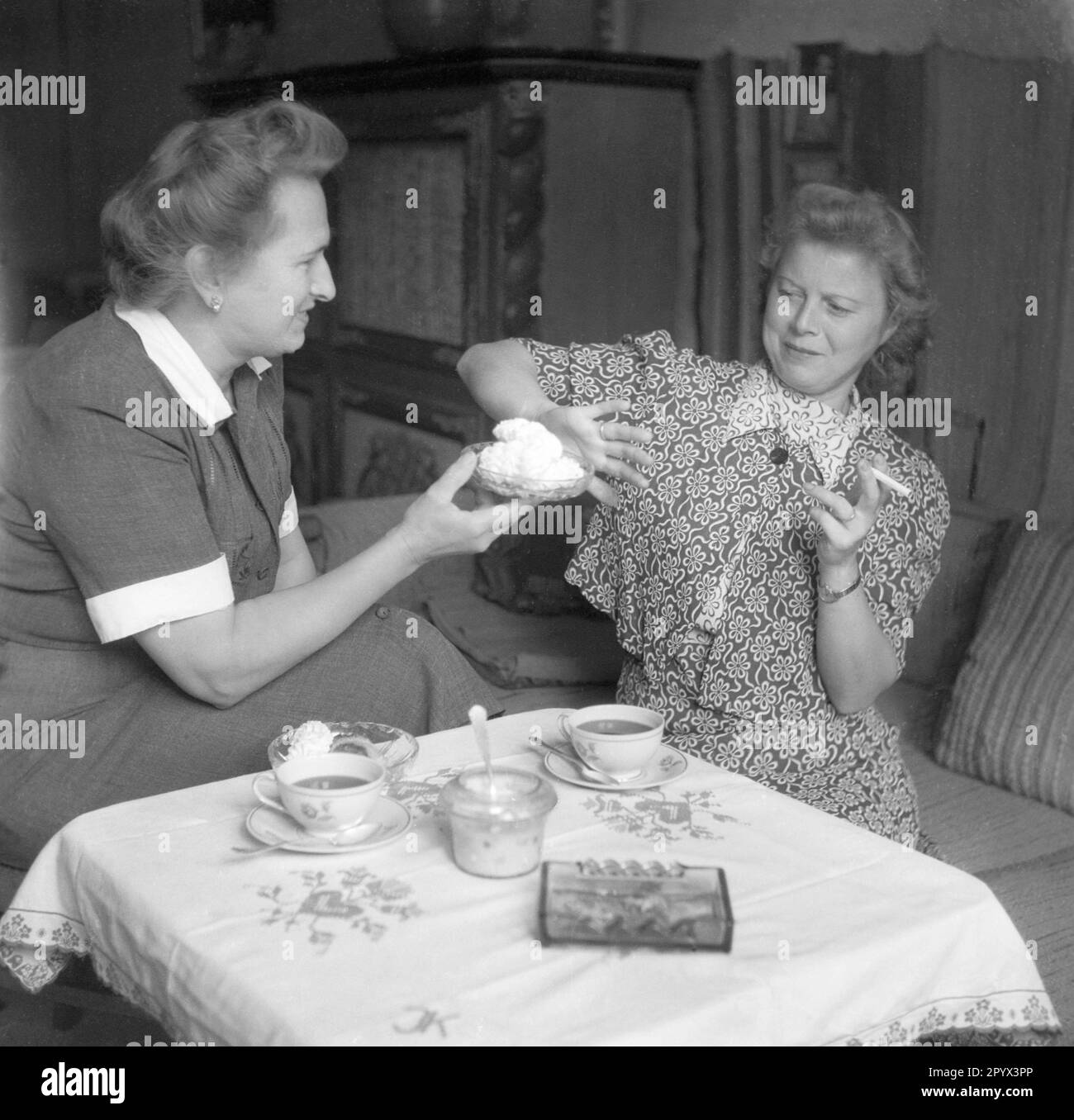 Una donna offre ad un'altra donna crema al caffè. Si rifiuta con una sigaretta in mano. Foto Stock
