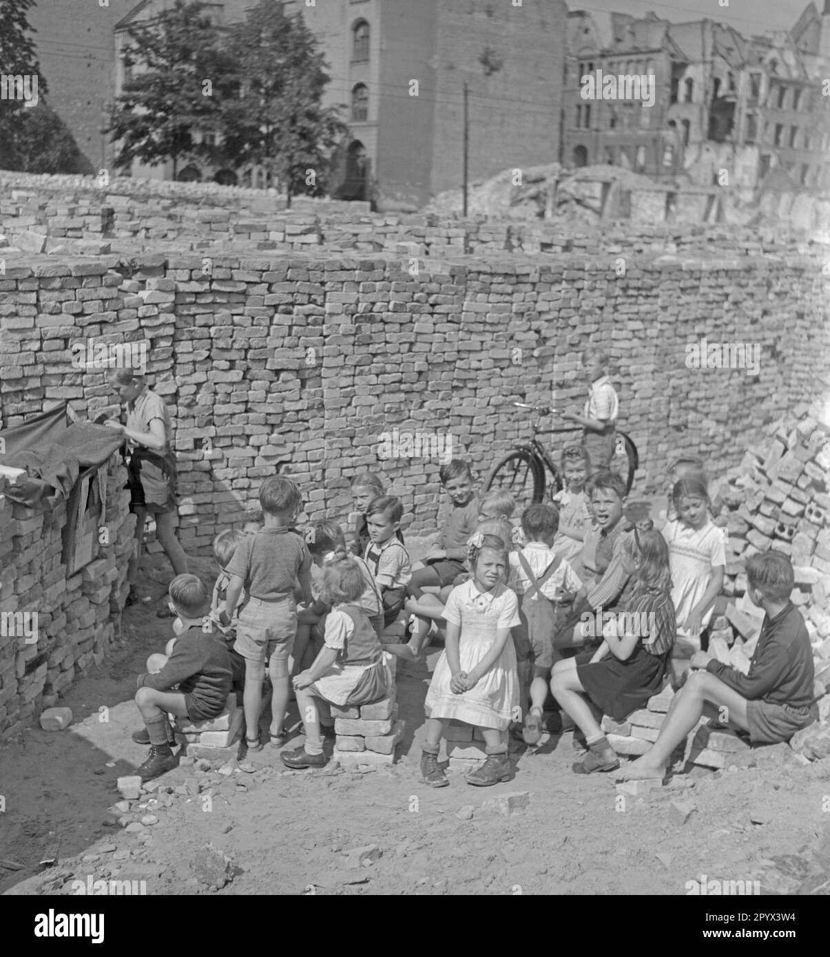 Foto non datata di un gruppo di bambini che guarda uno spettacolo di marionette tra mucchi di mattoni rimanenti dalle rovine. I mattoni servono come tenda del teatro delle marionette. Sullo sfondo, più pile di mattoni e case parzialmente distrutte da bombardamenti. Foto Stock