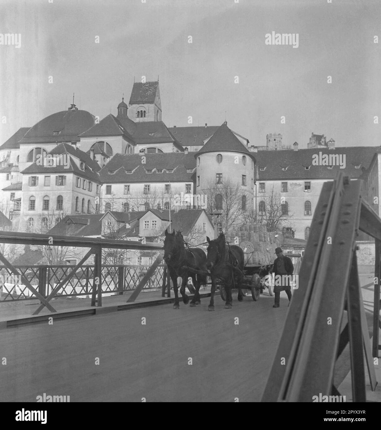 Un uomo conduce un carretto cavallo con barili su un ponte. Sullo sfondo è un castello. Foto Stock
