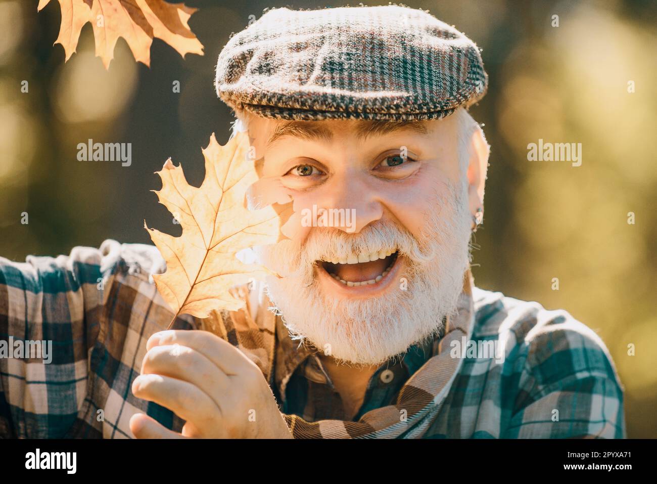 Gli anziani passeggiano in un parco in autunno. Vecchio solo nel parco autunnale. Anziano uomo anziano sullo sfondo dell'autunno - ritratto del volto primo piano. Foto Stock