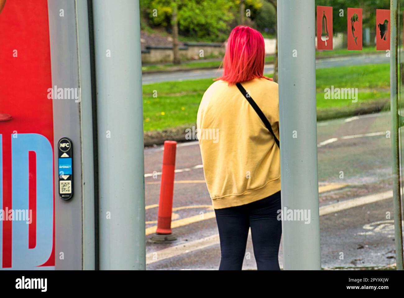 ragazza con capelli rossi rosa alla fermata dell'autobus in giallo Foto Stock