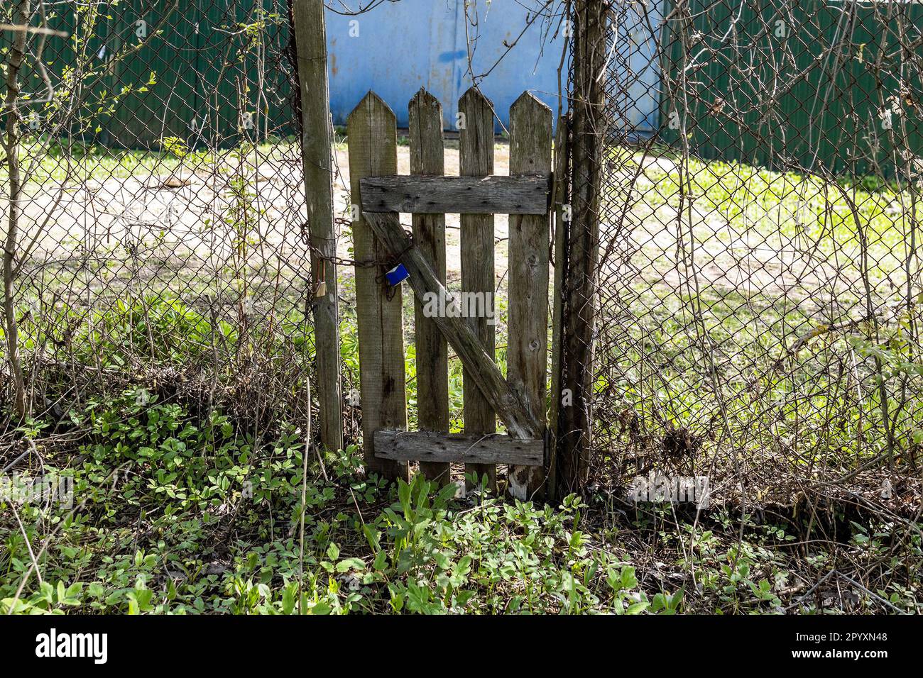 vecchio scabby wicket in legno in catena-link recinto nel villaggio Foto Stock