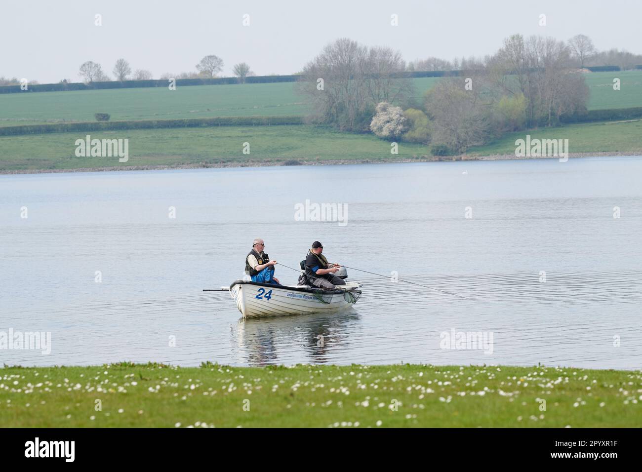 Un paio di pescatori pescano con le loro canne da una barca a remi motorizzata su un lago. Foto Stock