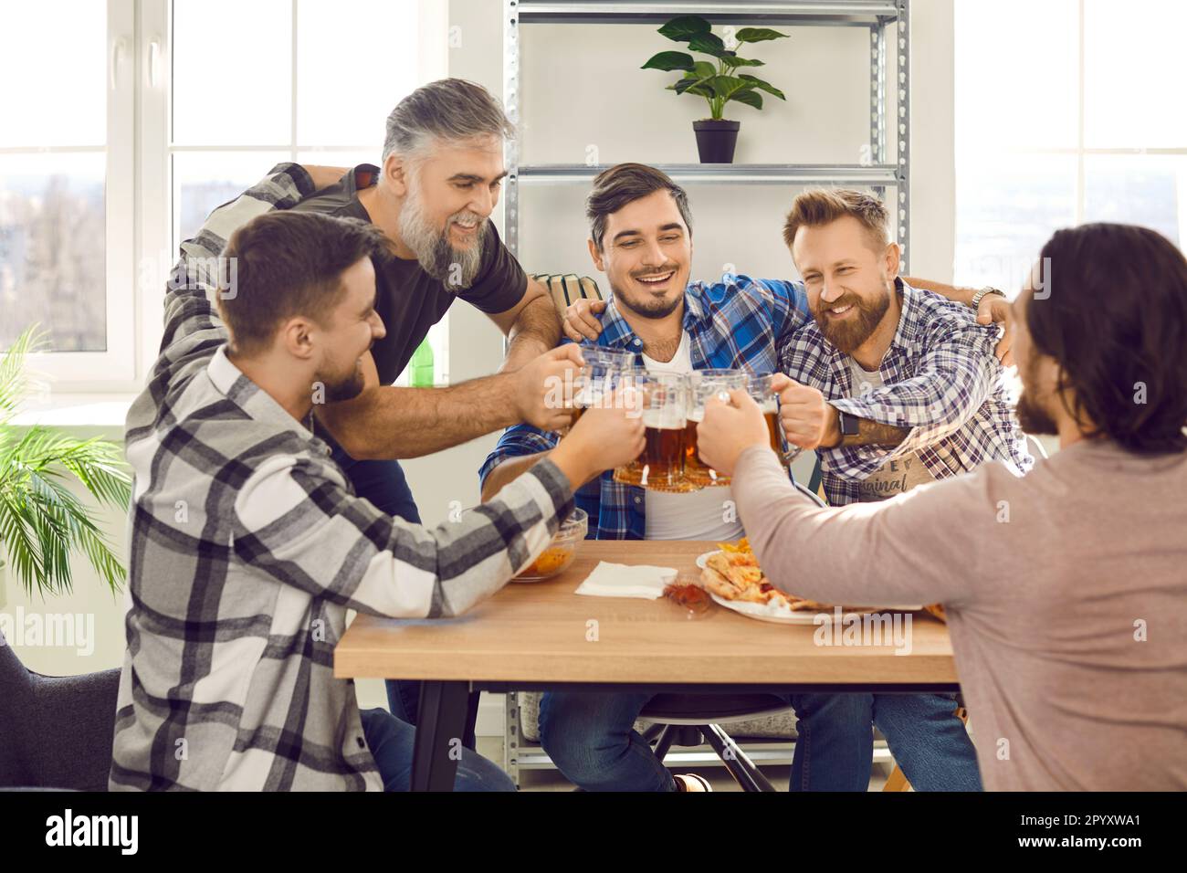 Felici amici maschi bearded bere birra e mangiare pizza alla festa a casa. Foto Stock