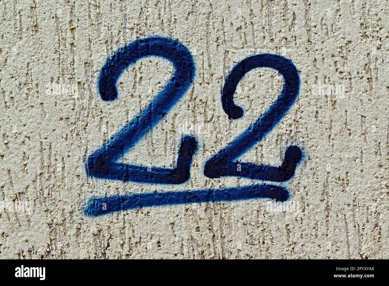 Il numero 22 è dipinto di blu su una parete grigia Foto Stock