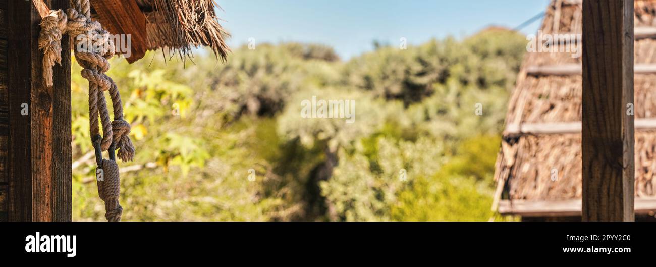 Spesso corda in fibra naturale nodo legato alla capanna della spiaggia, sfondo di alberi sfocati Foto Stock