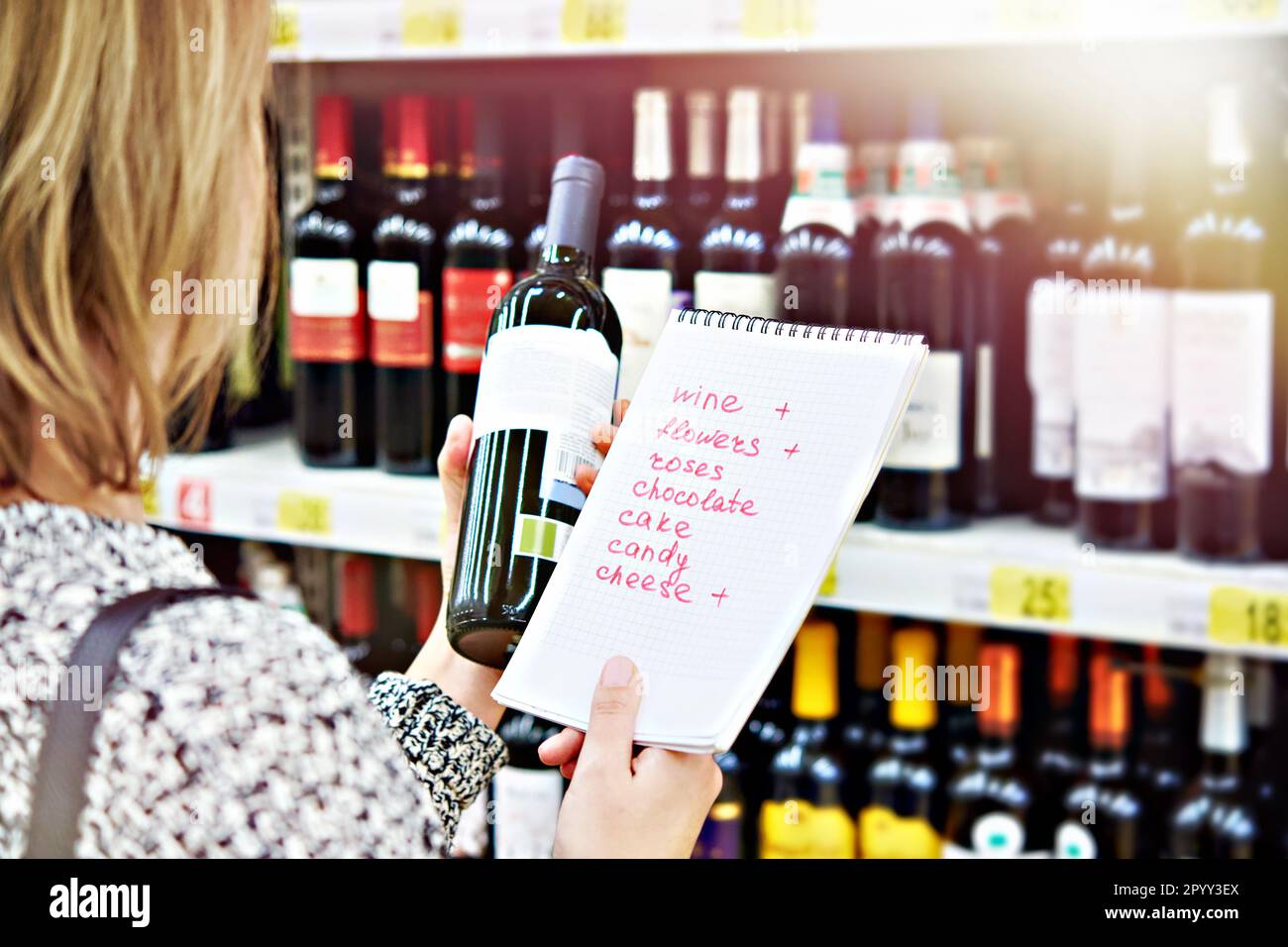 La ragazza sceglie una bottiglia di vino per la data nel negozio Foto Stock