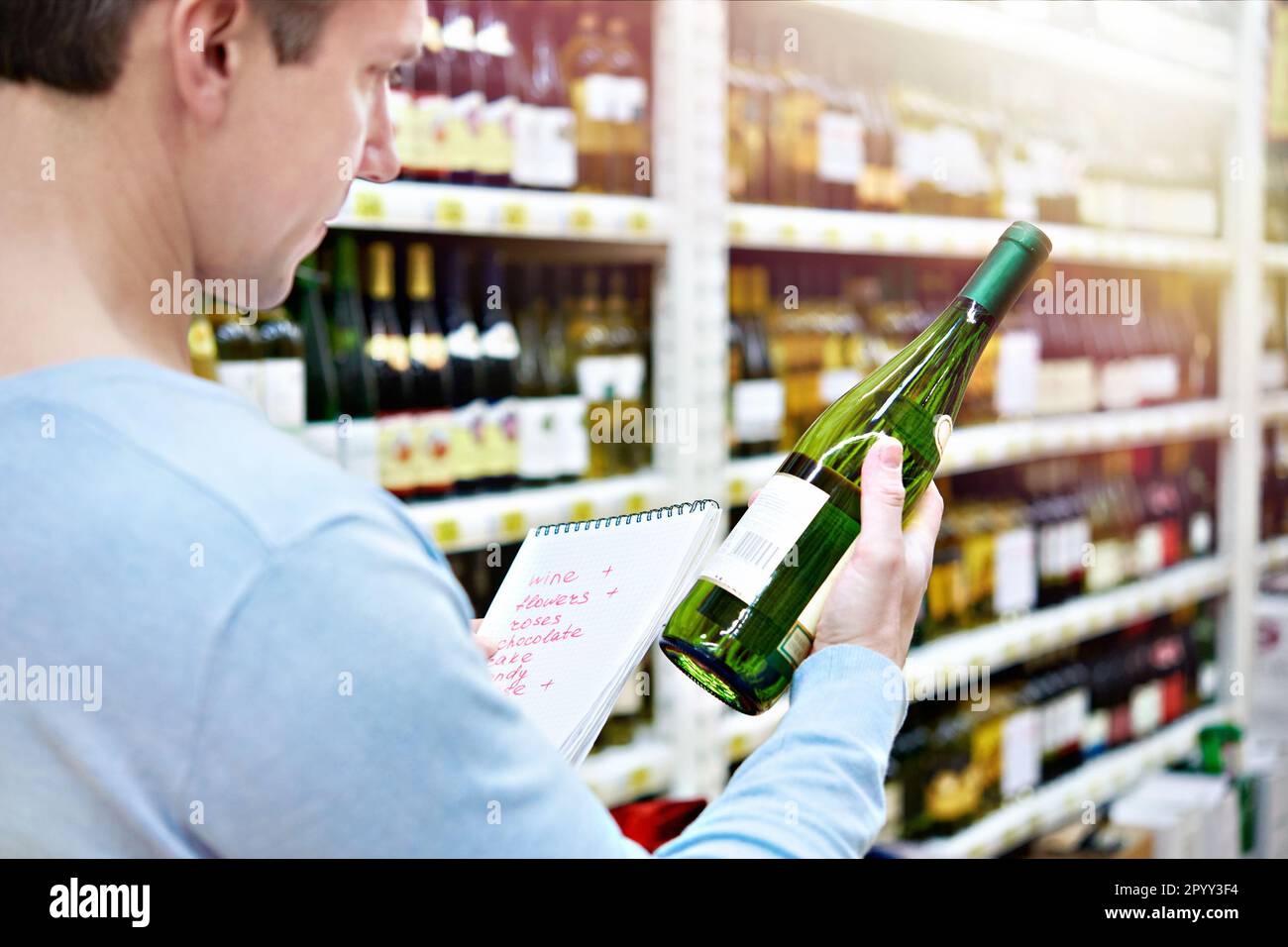 L'uomo sceglie una bottiglia di vino per la data in negozio Foto Stock