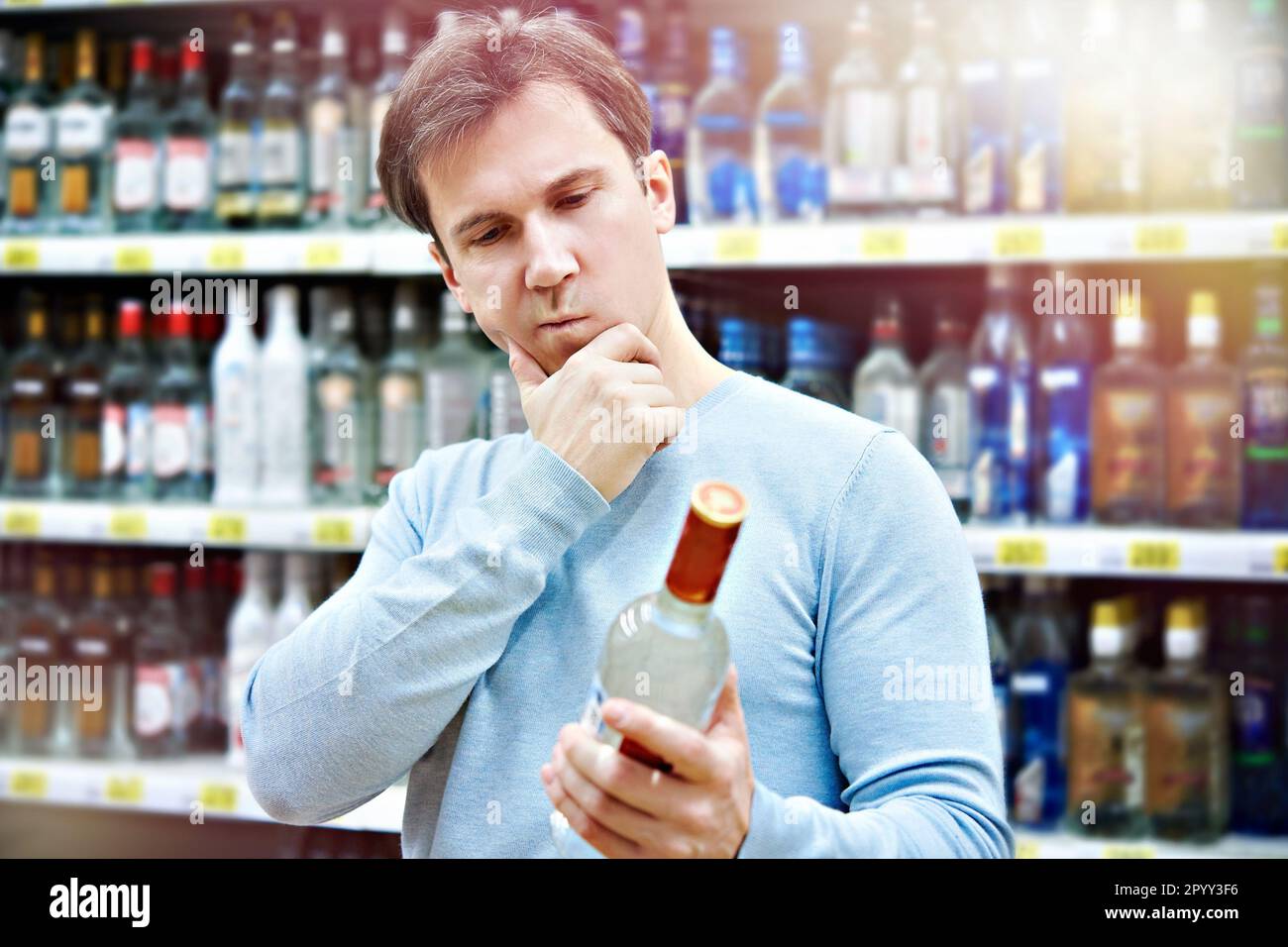 L'uomo sceglie una bottiglia di vodka nel negozio Foto Stock
