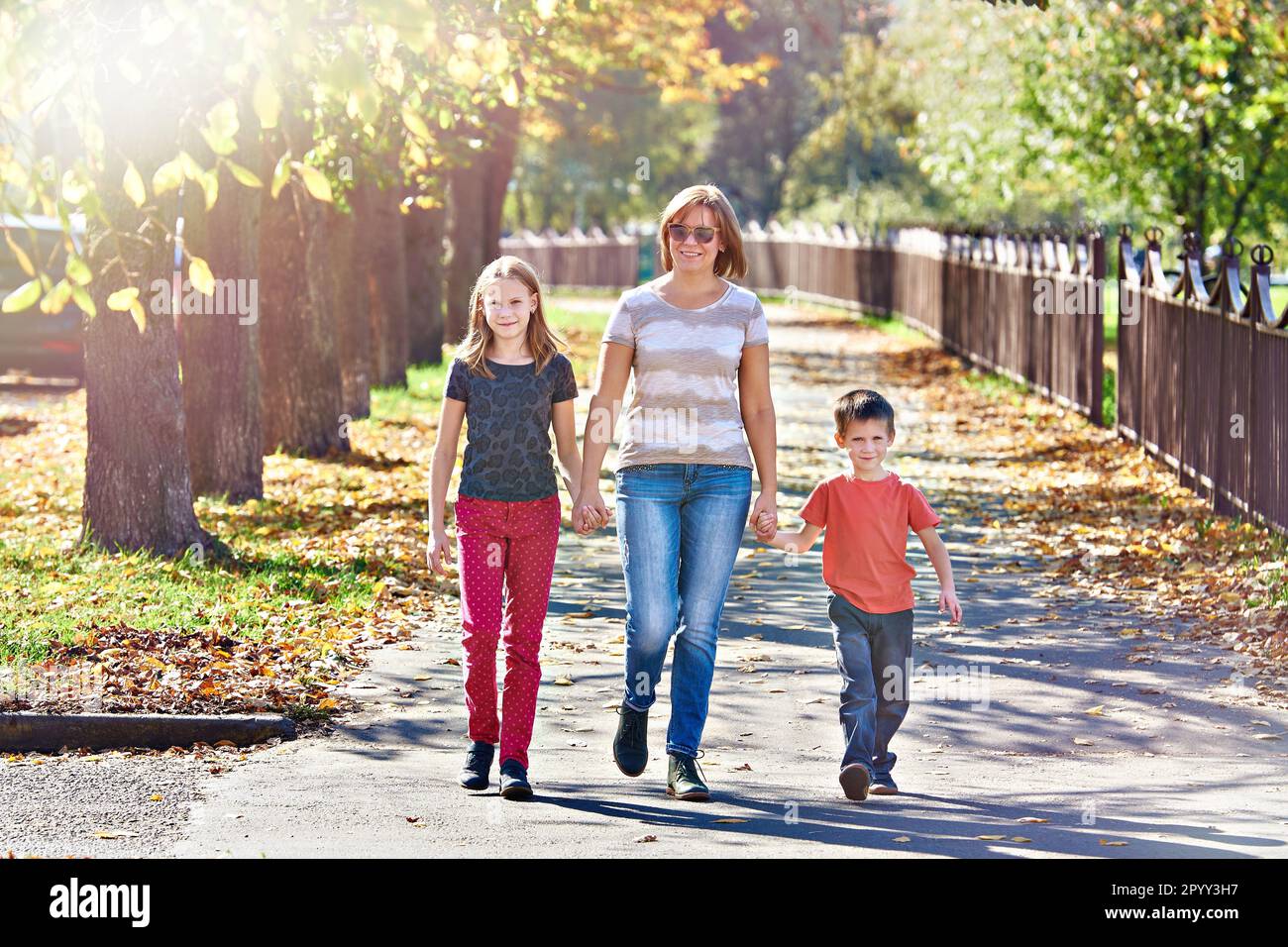 Madre con bambini che camminano nel parco autunnale in una giornata di sole Foto Stock
