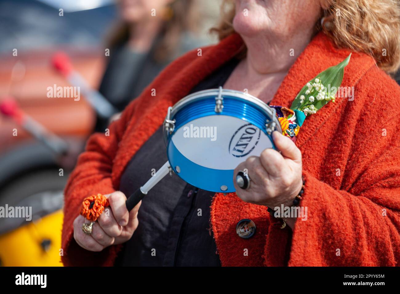 Carhaix, Francia - Maggio 1 2023: Manifestazione contro la riforma pensionistica con una donna anziana che batte un tamburello in disapprovazione. Foto Stock