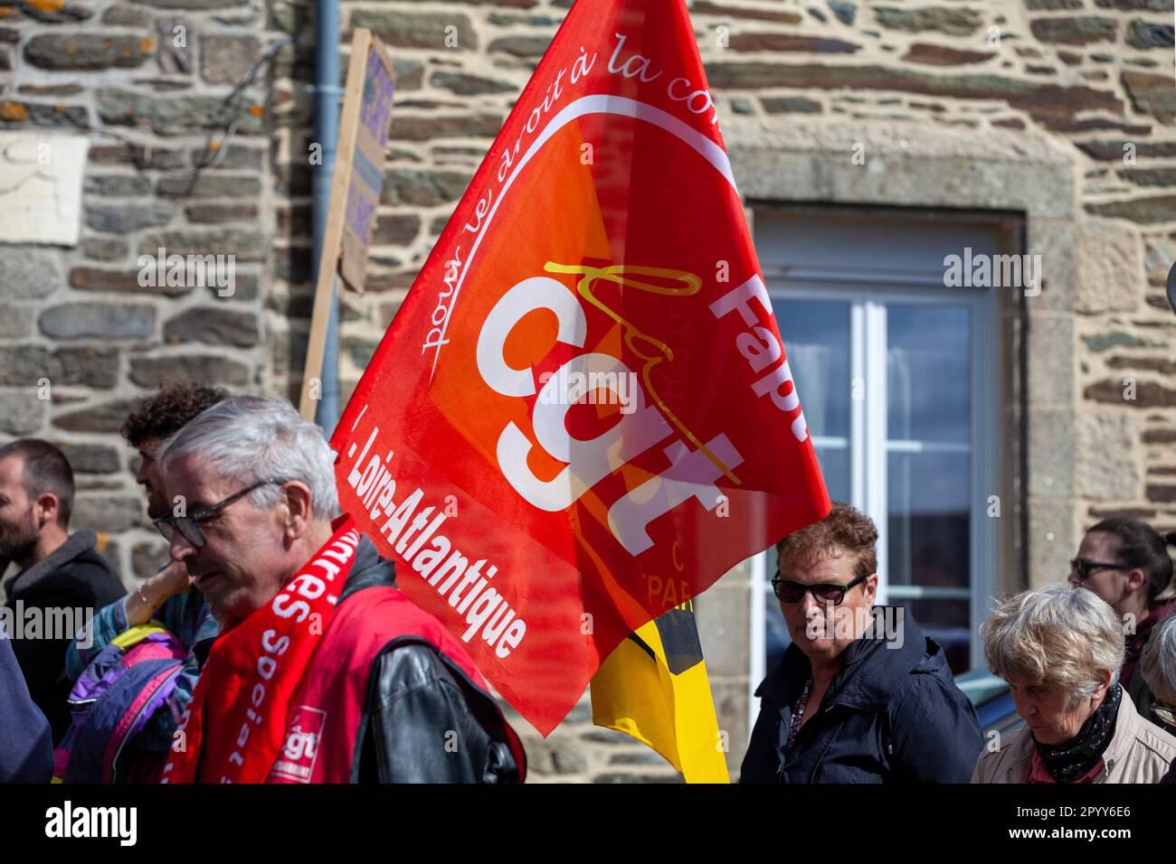 Carhaix, Francia - Maggio 1 2023: Manifestazione contro la riforma pensionistica con un dimostratore che sventola una bandiera CGT, un centro sindacale nazionale. Foto Stock