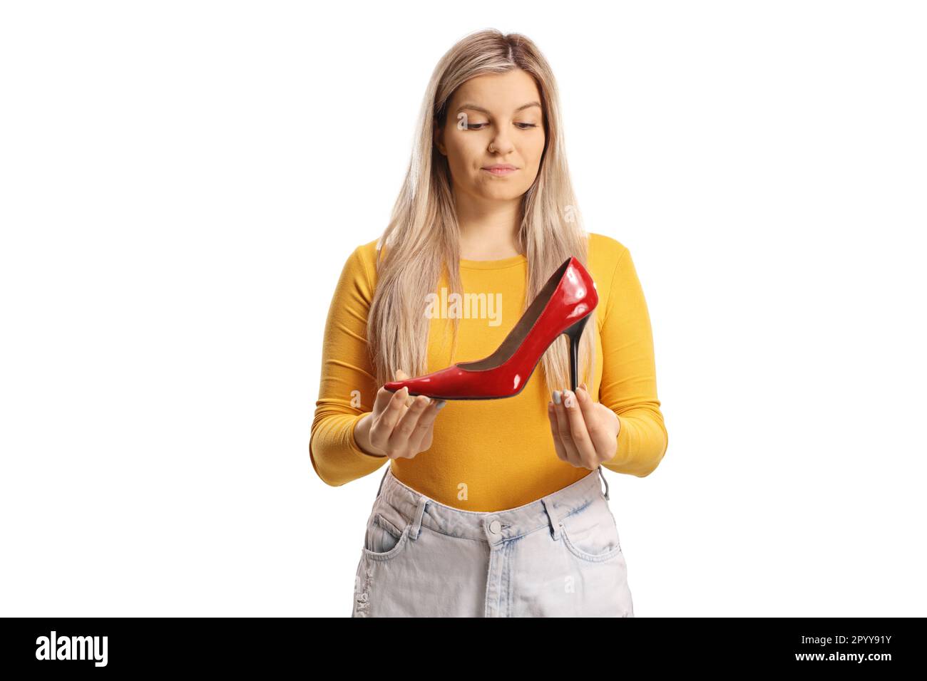 Giovane donna casual che tiene una scarpa rossa alto tacco e pensare isolato su sfondo bianco Foto Stock