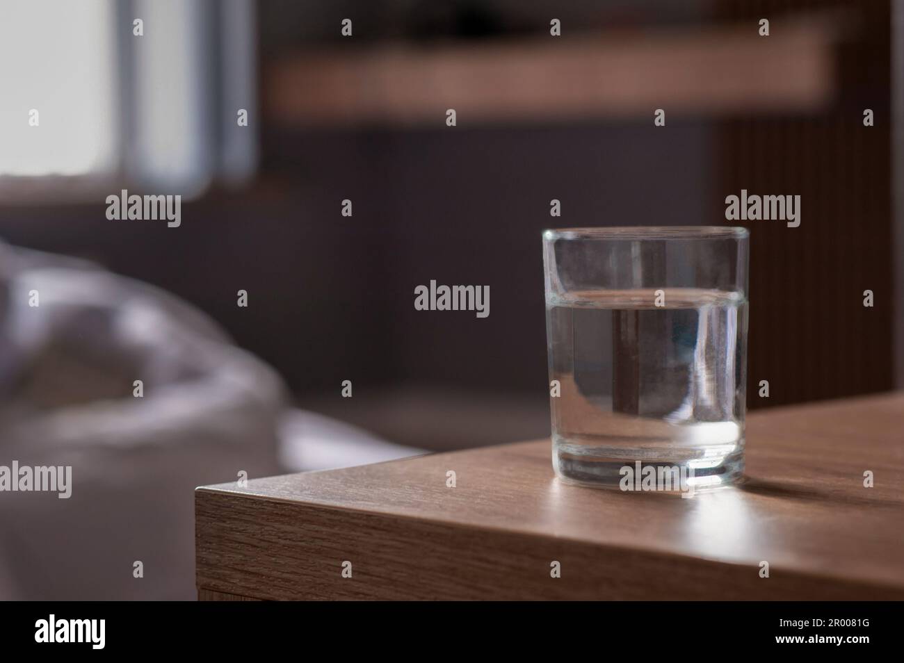 Bicchiere d'acqua sul tavolo in legno in camera. Spazio per il testo Foto Stock