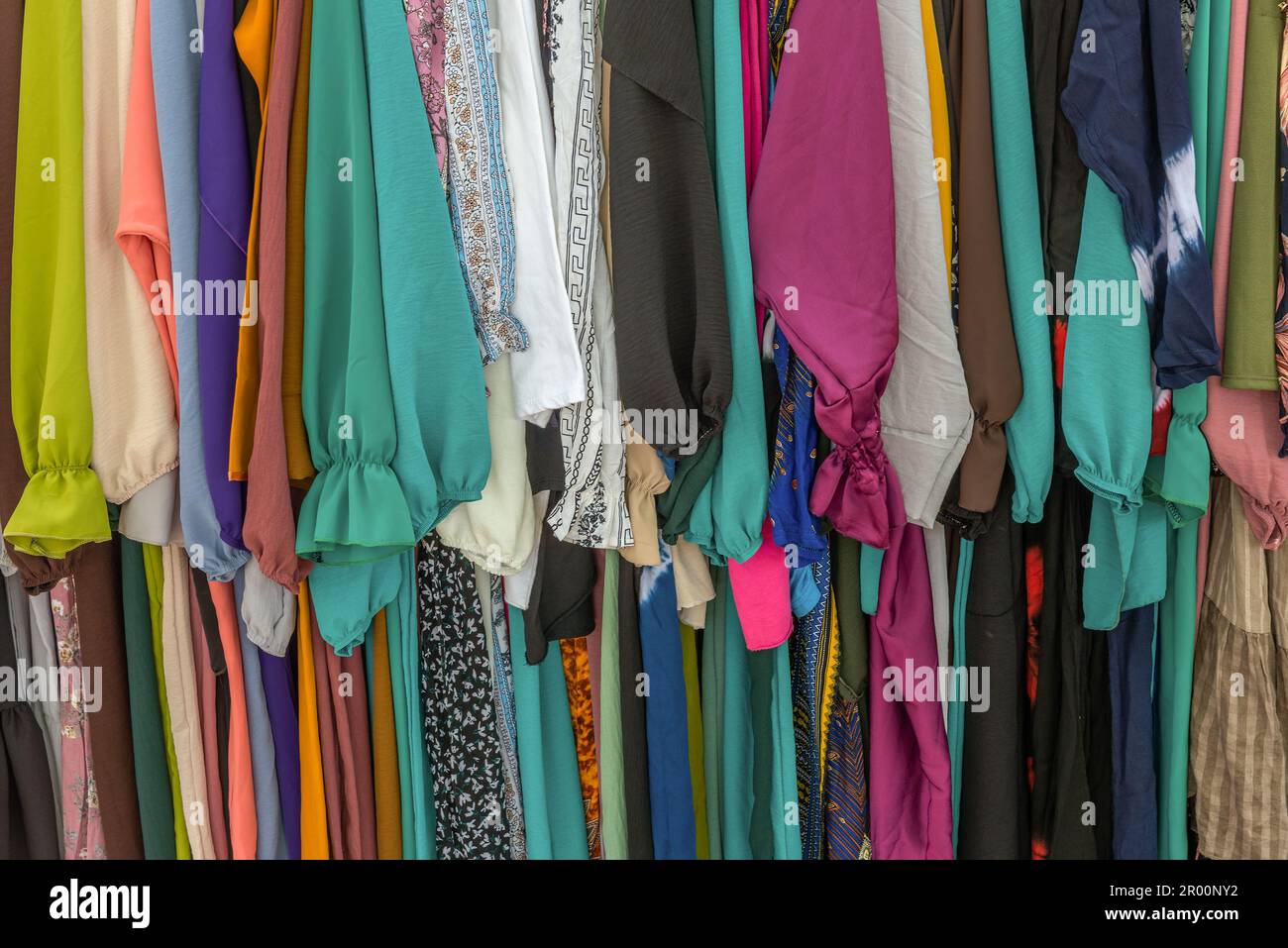 usato abiti colorati appesi su una cremagliera in un mercato delle pulci Foto Stock