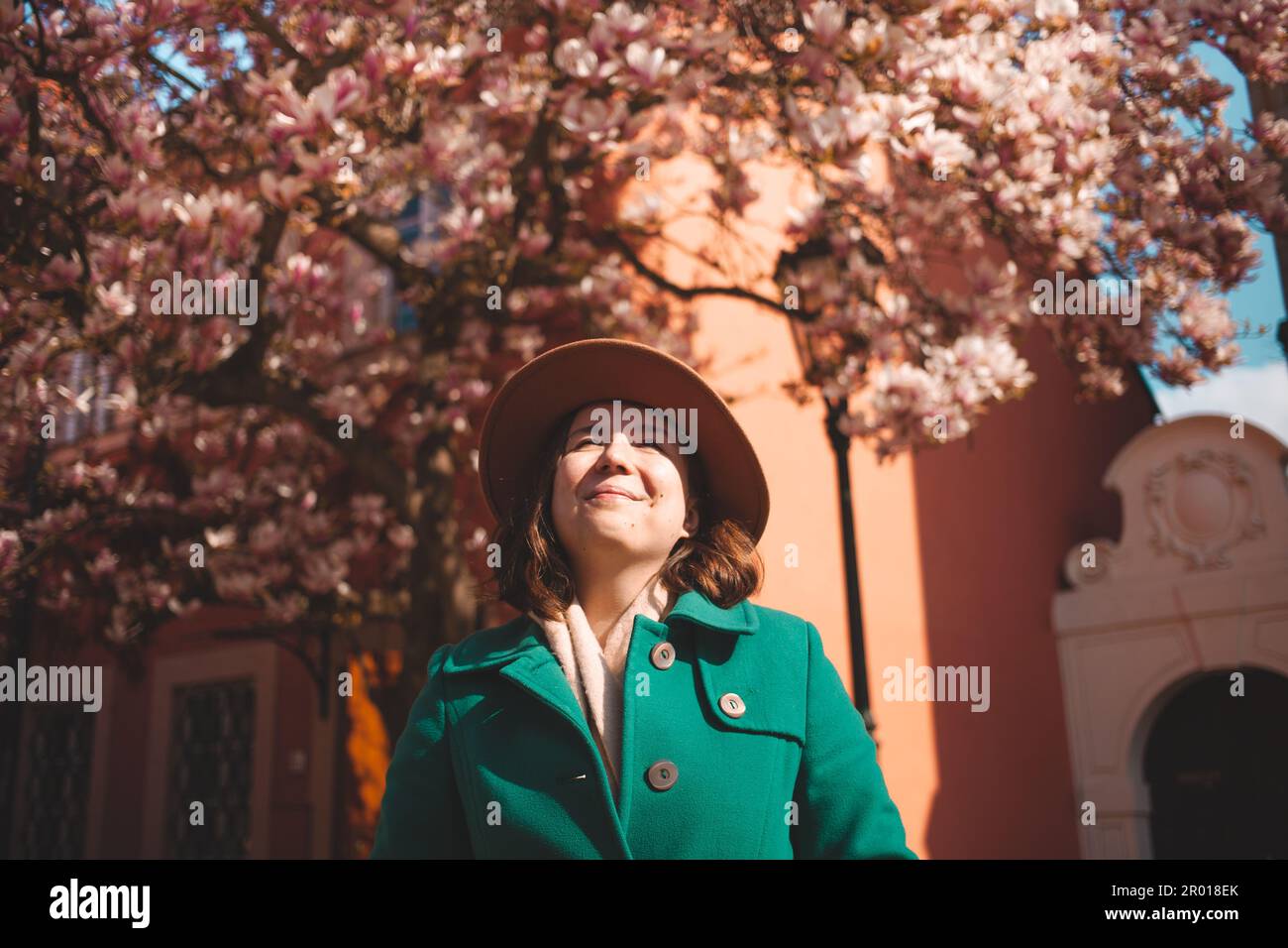 Donna cammina per Praga, gode del sole e del bel tempo, si trova sotto il bellissimo albero di magnolia. Luce intensa. Foto Stock