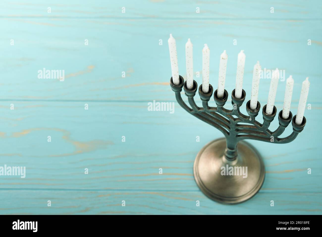 Hanukkah felice. Hanukkah vecchio Menorah sullo sfondo della bandiera israeliana con luce solare o bokeh su sfondo di legno bianco. Immagine religiosa dei gioielli Foto Stock