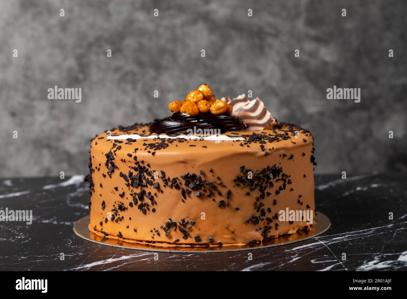 Torta di crema al caramello. Torta di compleanno o di festa. Torta con caramello e crema al cioccolato su fondo scuro. Foto Stock