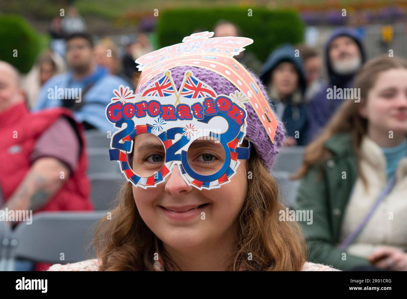 Edimburgo, Scozia, Regno Unito. 6 maggio 2023. Scene da Edimburgo il giorno dell'incoronazione di re Carlo III Membro del pubblico che indossa una corona di cartone e occhiali da incoronazione nei giardini di West Princes Street. Iain Masterton/Alamy Live News Foto Stock
