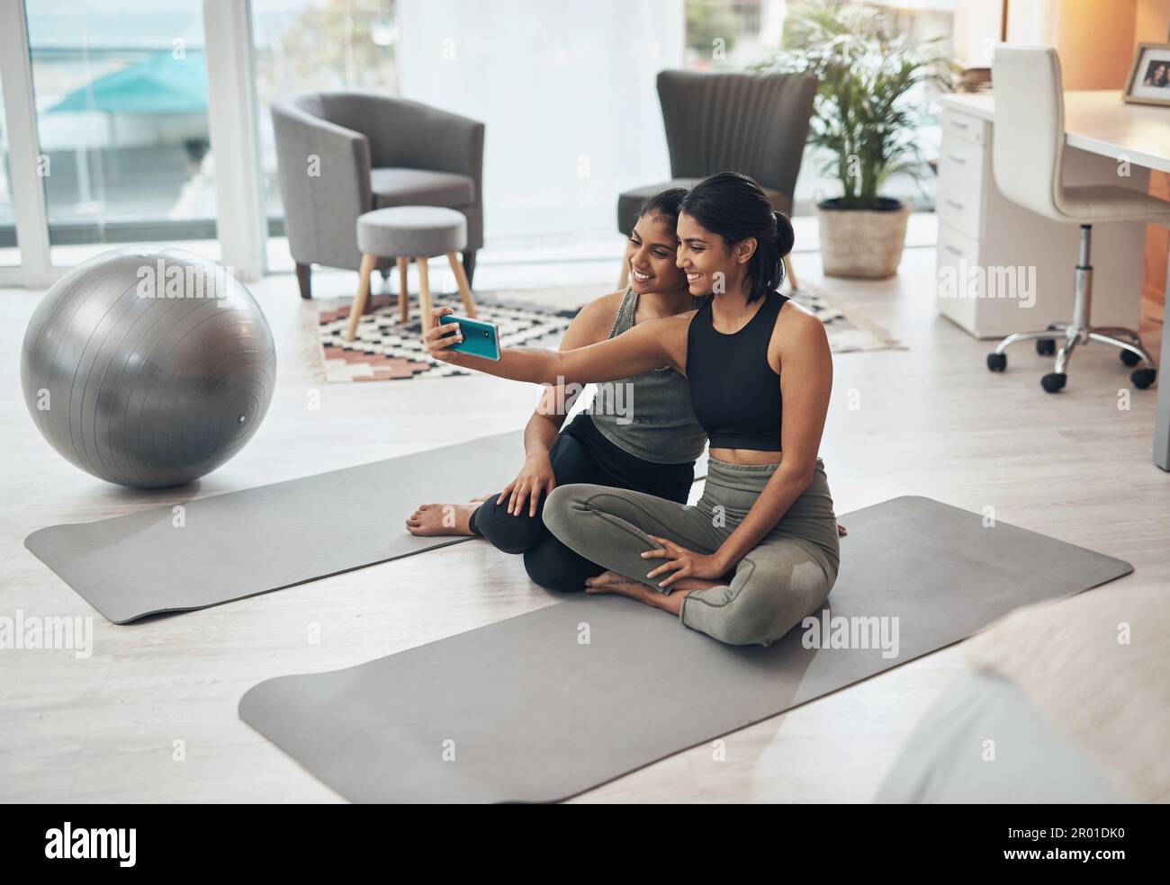 Per stare in forma nel comfort di casa nostra. due giovani donne che  prendono un selfie mentre si siedono a casa in abiti da ginnastica Foto  stock - Alamy