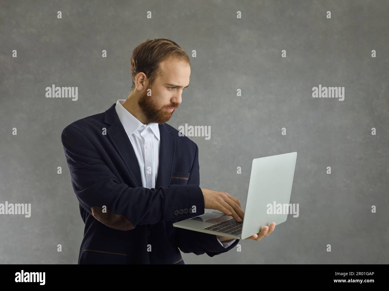 Studio ritratto di adulto serio concentrato uomo d'affari caucasico utilizzando il portatile Foto Stock