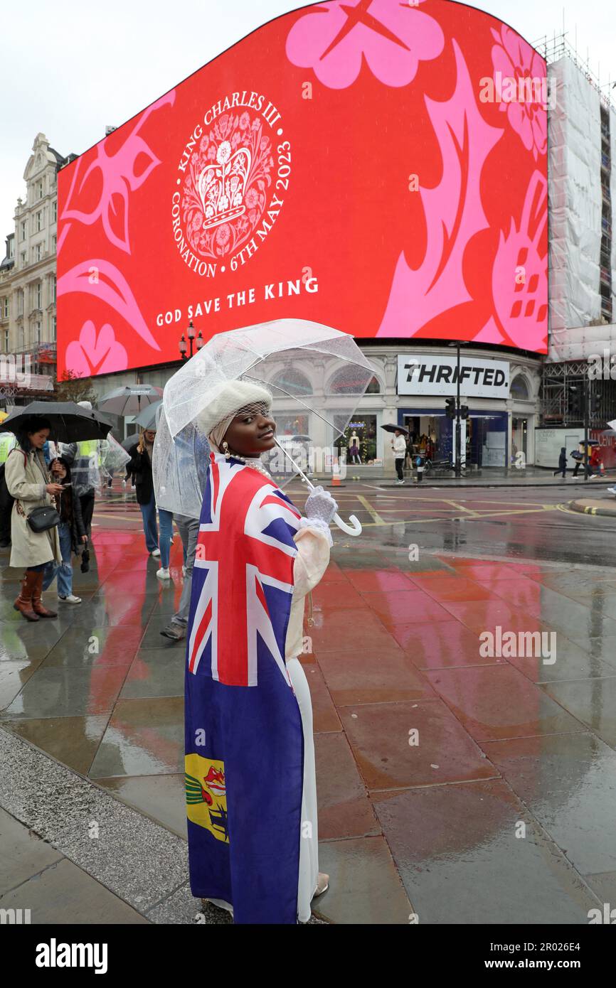 Londra, Regno Unito. 6th maggio, 2023. Sostenitore con bandiera Union Jack rossa, bianca e blu che guarda il messaggio di incoronazione per l'incoronazione di Re Carlo III, a Piccadilly Circus, Londra dicendo felice e glorioso e Dio Salva il Re credito: Paul Brown/Alamy Live News Foto Stock