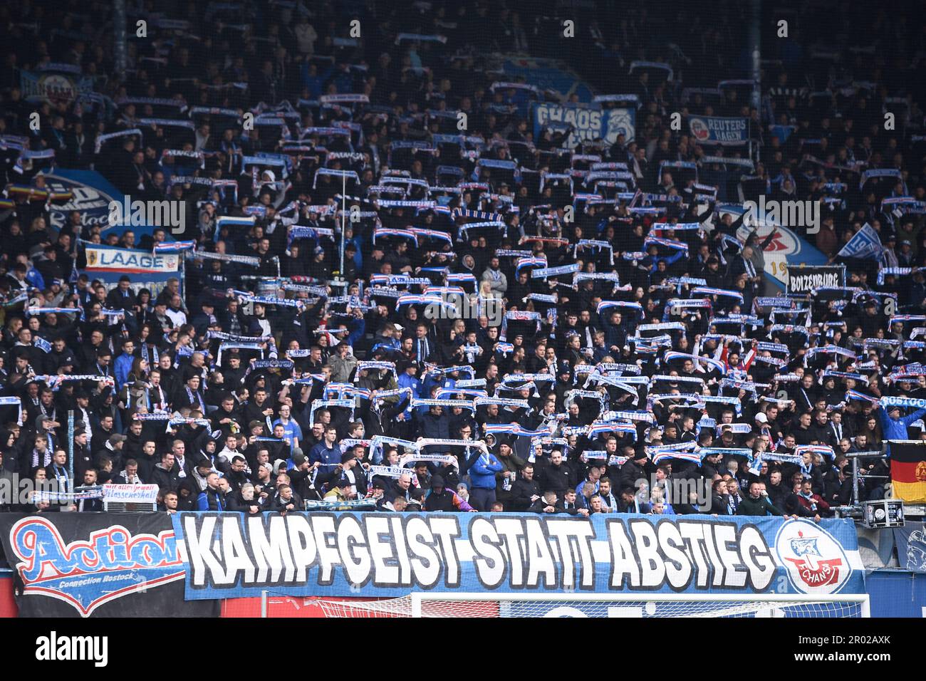 Rostock, Germania. 06th maggio, 2023. Calcio: 2nd Bundesliga, Hansa Rostock - Jahn Regensburg, giorno 31, Ostseestadion. I fan dei supporti tengono le sciarpe dei fan prima dell'inizio del gioco. Un banner recita 'Spirito combattente invece di retrocessione'. Credit: Gregor Fischer/dpa - NOTA IMPORTANTE: In conformità ai requisiti della DFL Deutsche Fußball Liga e del DFB Deutscher Fußball-Bund, è vietato utilizzare o utilizzare fotografie scattate nello stadio e/o della partita sotto forma di sequenze di immagini e/o serie di foto simili a video./dpa/Alamy Live News Foto Stock