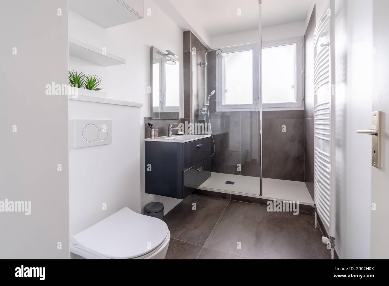 Home bagno, luminoso nuovo bagno interno con piastrelle di vetro doccia, mobile, interni progettati bianco e con piastrelle nere Foto Stock