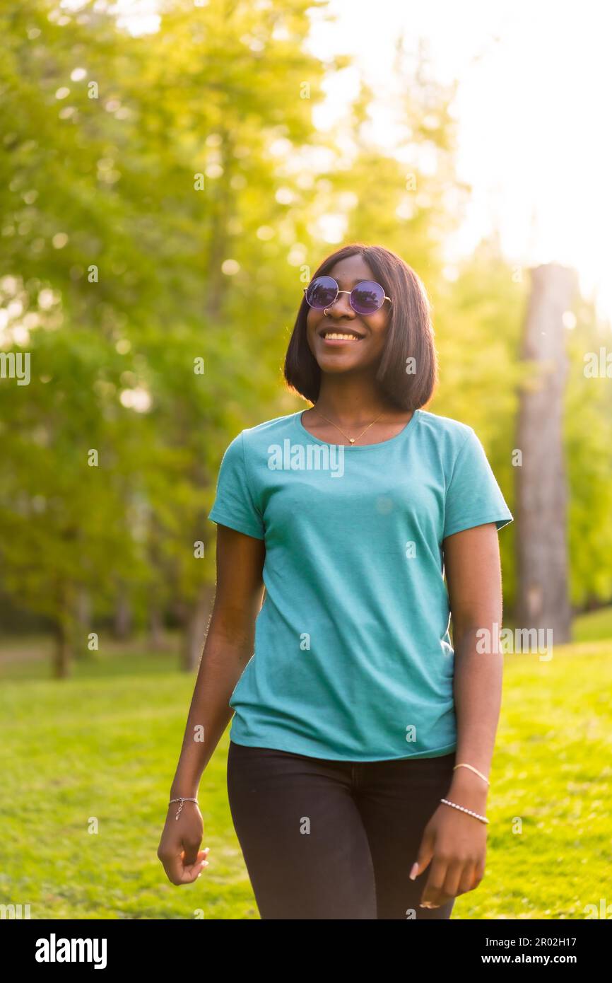 Fuga tranquilla: Stile di vita Ritratto di un afro-americano femmina Turismo con occhiali da sole nel bosco al tramonto Foto Stock