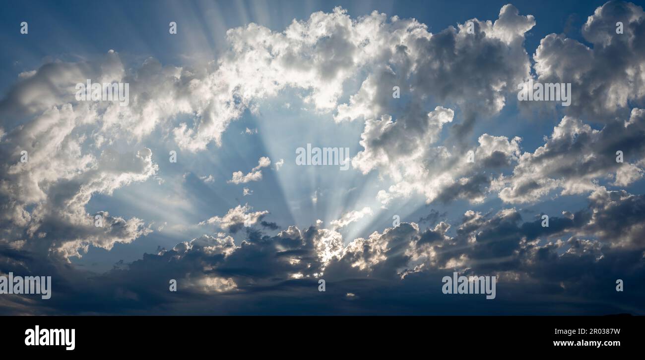 Vista panoramica della spettacolare vista dei raggi solari che si diffondono attraverso le nuvole luminose nel cielo blu Foto Stock