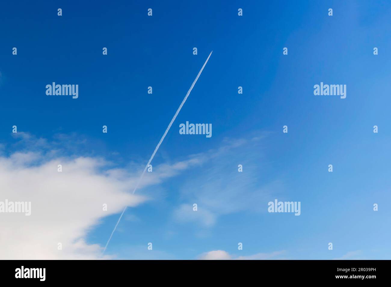 Un jet plane privato che vola con sentieri a contralto o a vapore su sfondo cielo blu Foto Stock