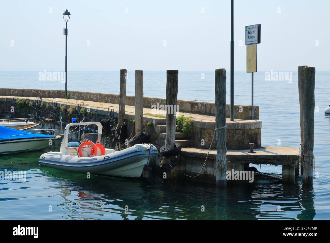 Barca bianca al molo nella piccola cittadina italiana sul lago di Garda Foto Stock