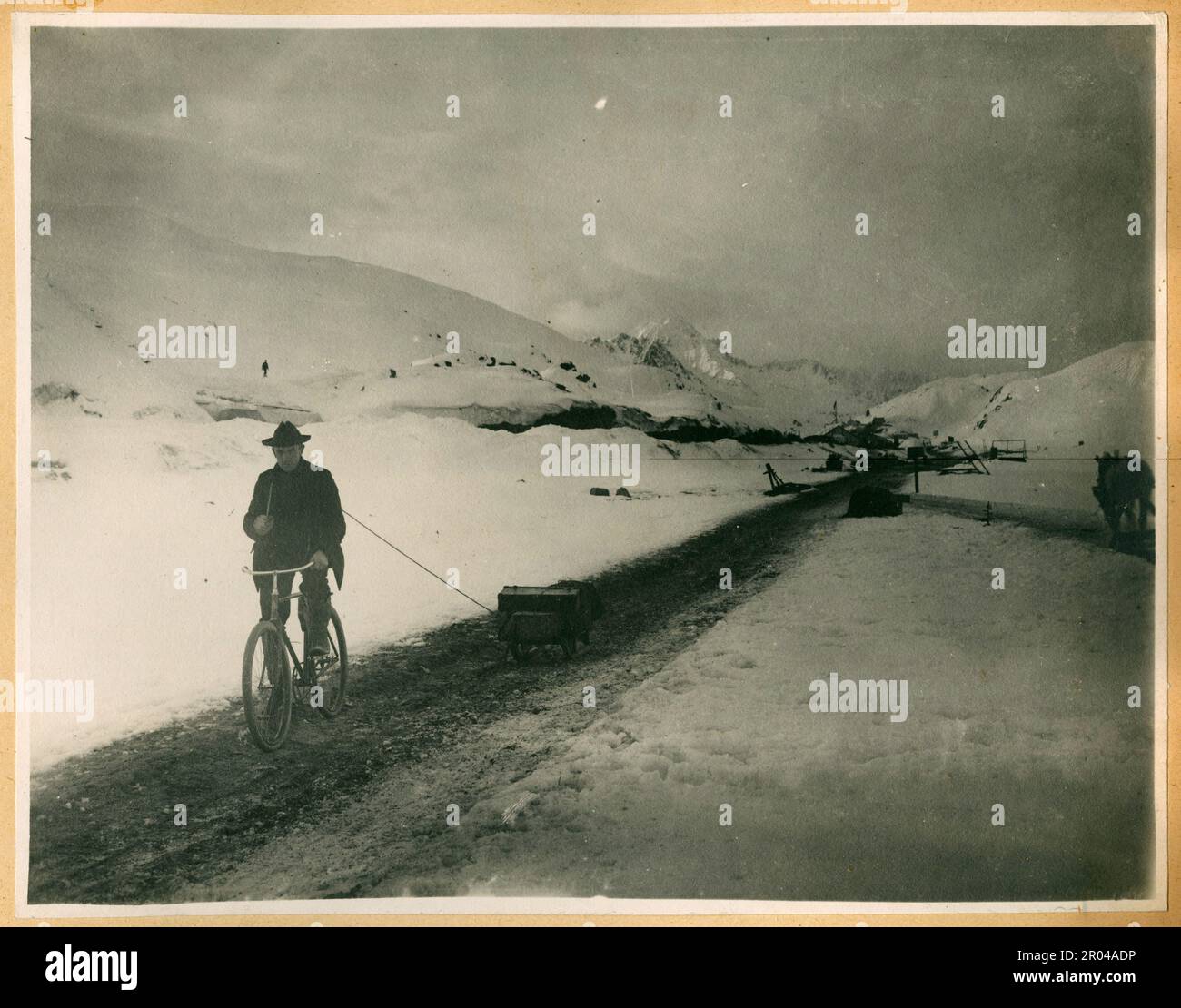 Un uomo in bicicletta che tira una slitta vicino alla cima del White Pass Trail, ca. 1899. Il Passo Bianco era una delle vie principali utilizzate dai prospettori che viaggiavano da Skagway ai campi d'oro dello Yukon.; Foto Stock