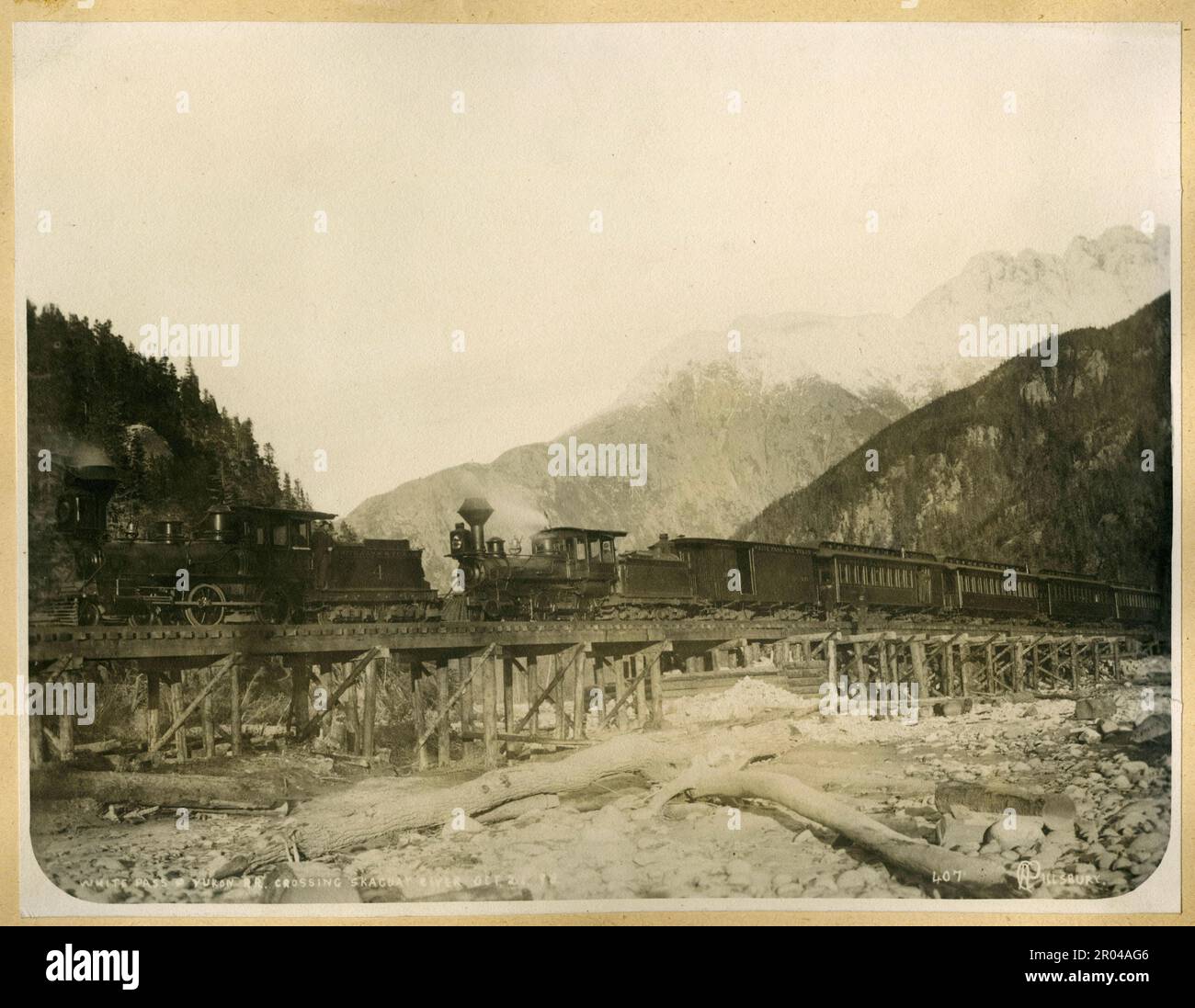 White Pass e Yukon treno ferroviario che attraversa il fiume Skagway, 21 ottobre 1898. Durante la corsa all'oro di Klondike, il Passo Bianco era una delle rotte usate dai cercatori per viaggiare da Skagway ai campi d'oro di Yukon. Nell'aprile del 1898, la White Pass and Yukon Railroad Company è stata fondata nel tentativo di stabilire un percorso più facile attraverso il passaggio. La costruzione della ferrovia iniziò il mese successivo. Migliaia di lavoratori hanno lavorato 24 ore su 24 in condizioni infide per completare il progetto. La ferrovia fu completata al Passo Bianco il 20 febbraio 1899 e raggiunse il Lago Bennett il 6 luglio 1899. Foto Stock