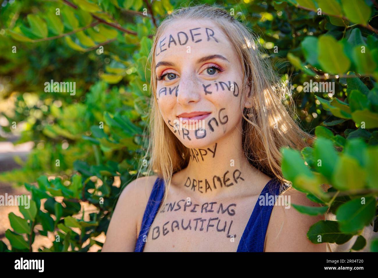 Ritratto di una giovane donna con parole motivazionali scritte sulla sua pelle, donna fiduciosa potenziata. Foto Stock