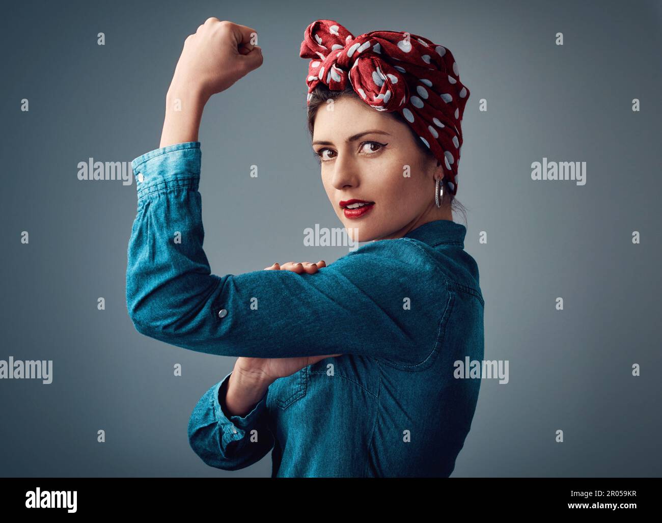La forza viene dall'interno. Studio ritratto di una giovane donna attraente flexing il suo bicep mentre in piedi su uno sfondo grigio. Foto Stock