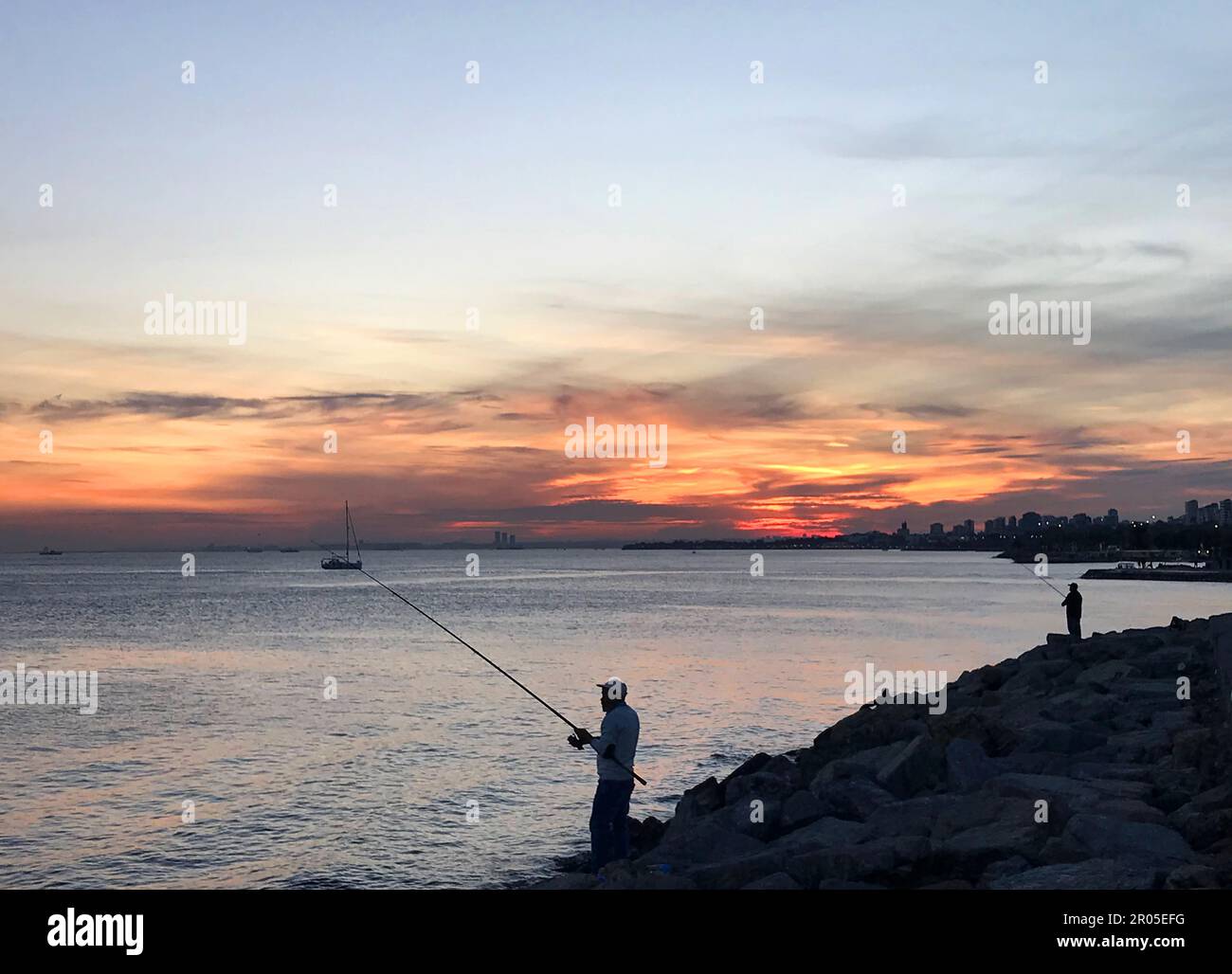 I pescatori dilettanti pescano sulla costa di Moda al tramonto a Istanbul, in Turchia. Foto Stock