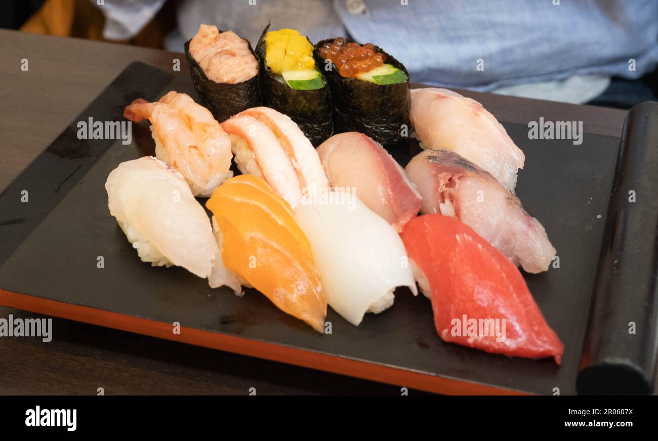 Un piatto con vari tipi di sushi temaki che includono salmone, gamberi e tonno in un ristorante di sushi. Foto Stock