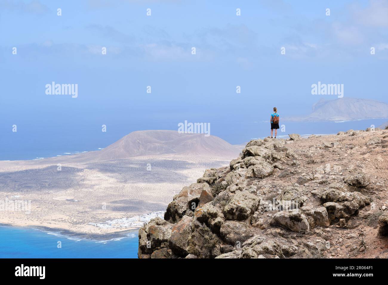 Escursionista ammirando il paesaggio da una collina, la Graciosa Isola sullo sfondo. Isole Canarie Foto Stock