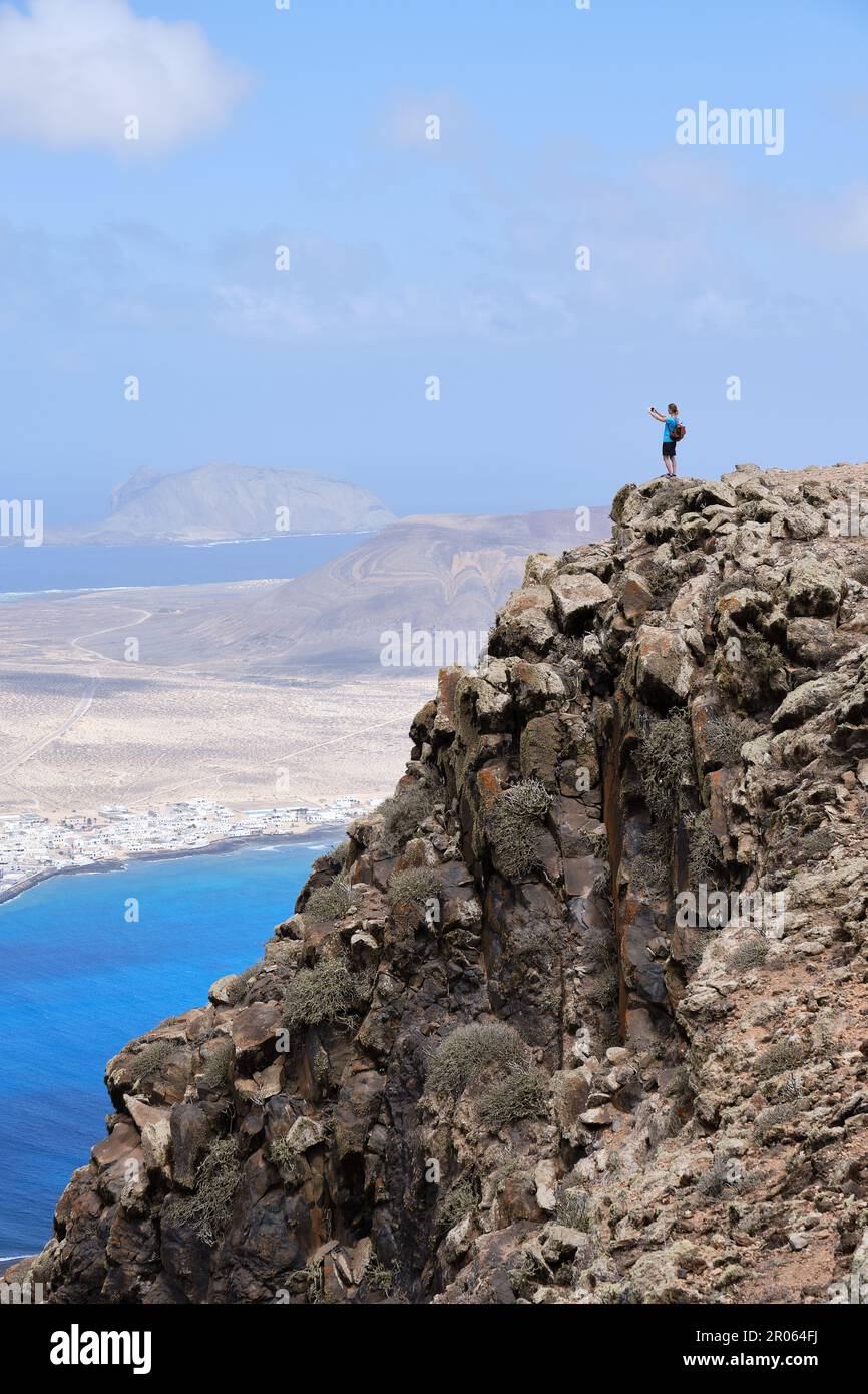 Donna che fotografa il paesaggio da una collina. Isola la Graciosa sullo sfondo. Foto Stock
