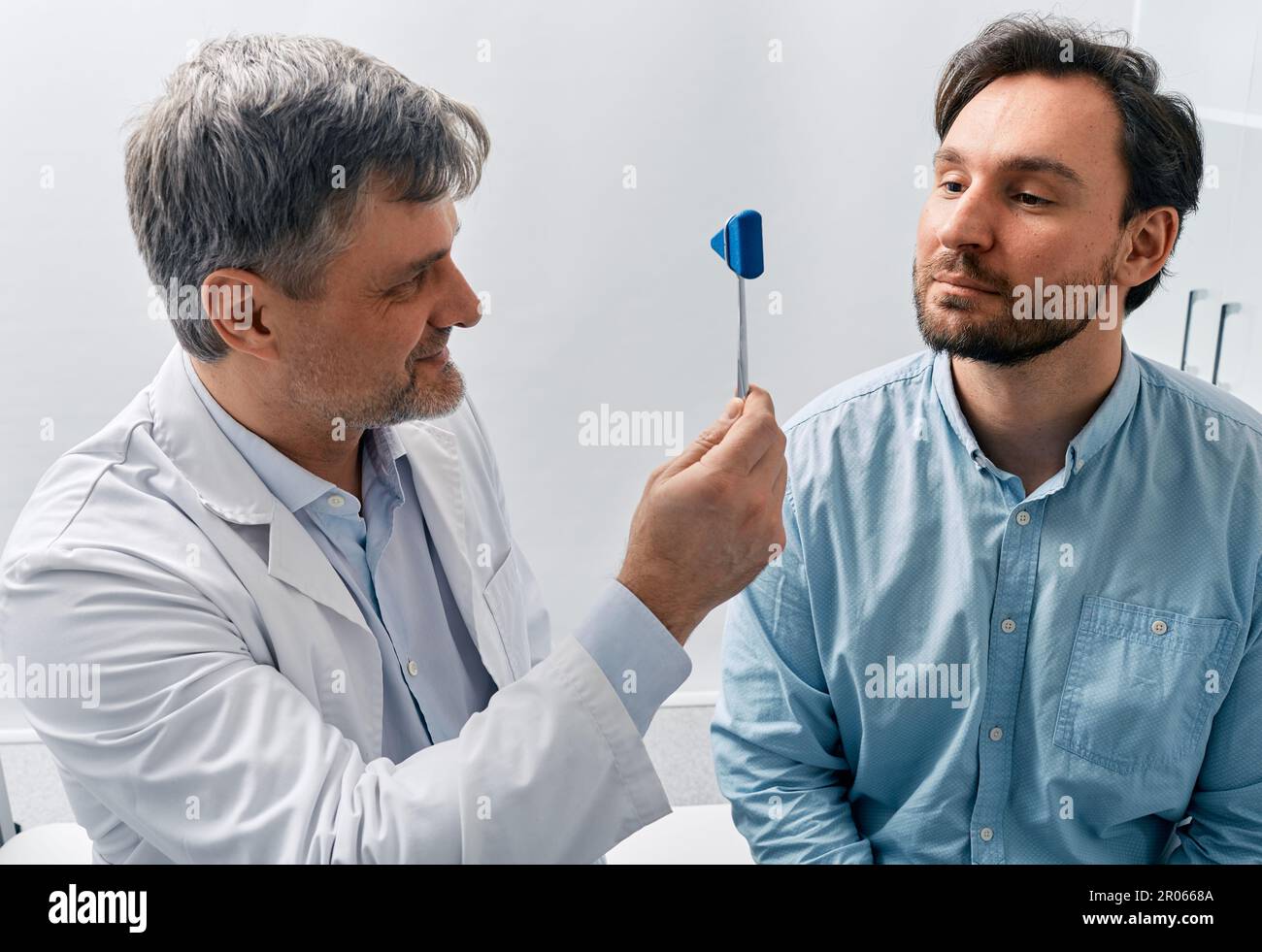 medico neurologo check-up sistema nervoso del paziente maschile e riflessi utilizzando martello neurologico in clinica medica. Esame neurologico Foto Stock