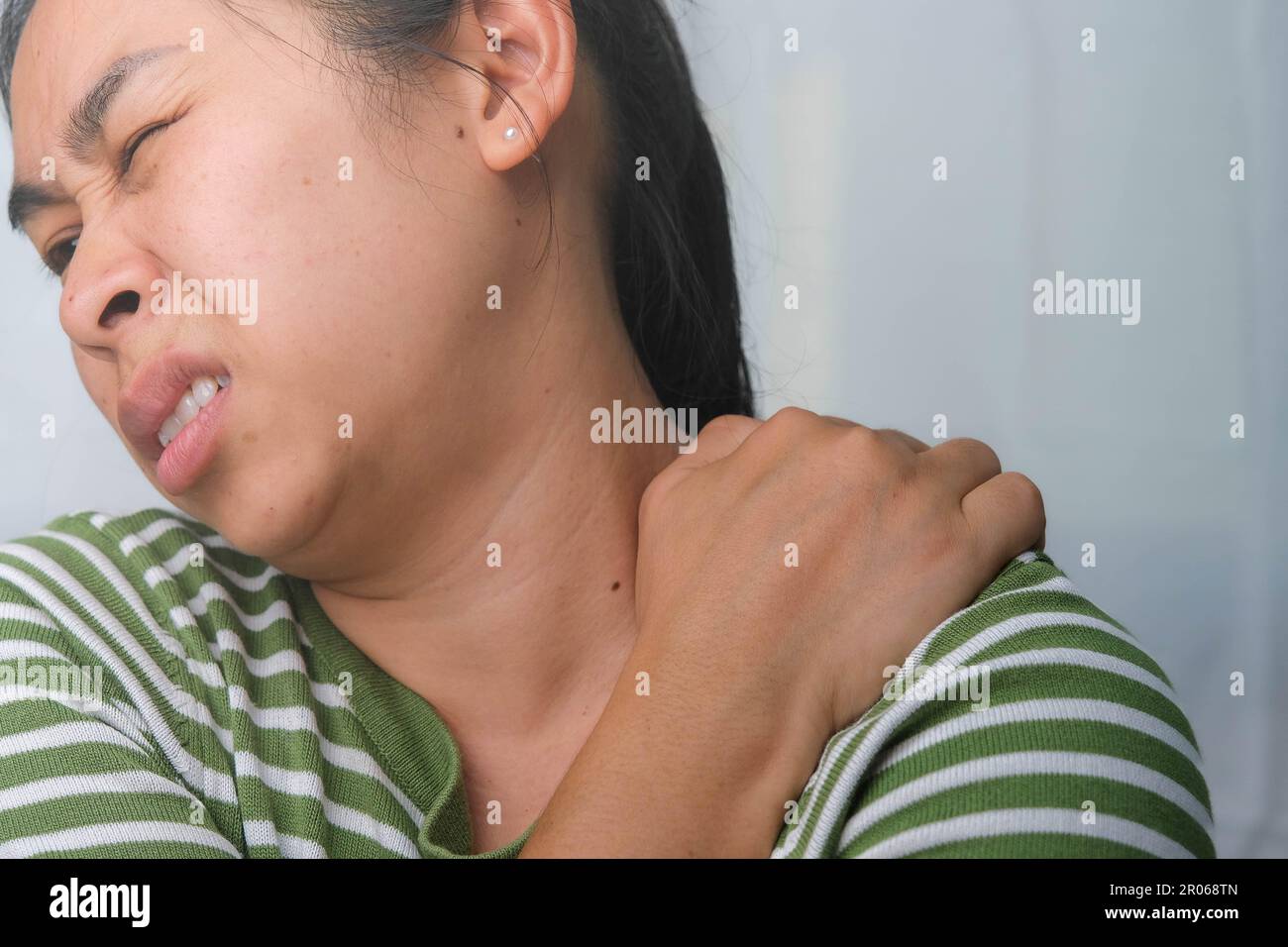 Moody giovane donna che tiene il collo. Donna stanca massaggiando il collo rigido, sforzando i muscoli, esausta dal lavoro. Dolore alla parte superiore del braccio. Sanità e medicina Foto Stock