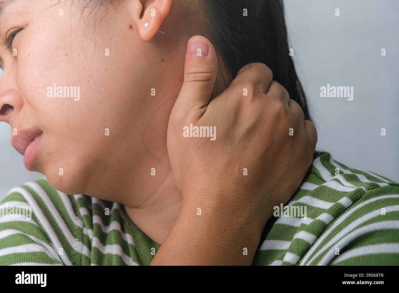 Moody giovane donna che tiene il collo. Donna stanca massaggiando il collo rigido, sforzando i muscoli, esausta dal lavoro. Dolore alla parte superiore del braccio. Sanità e medicina Foto Stock