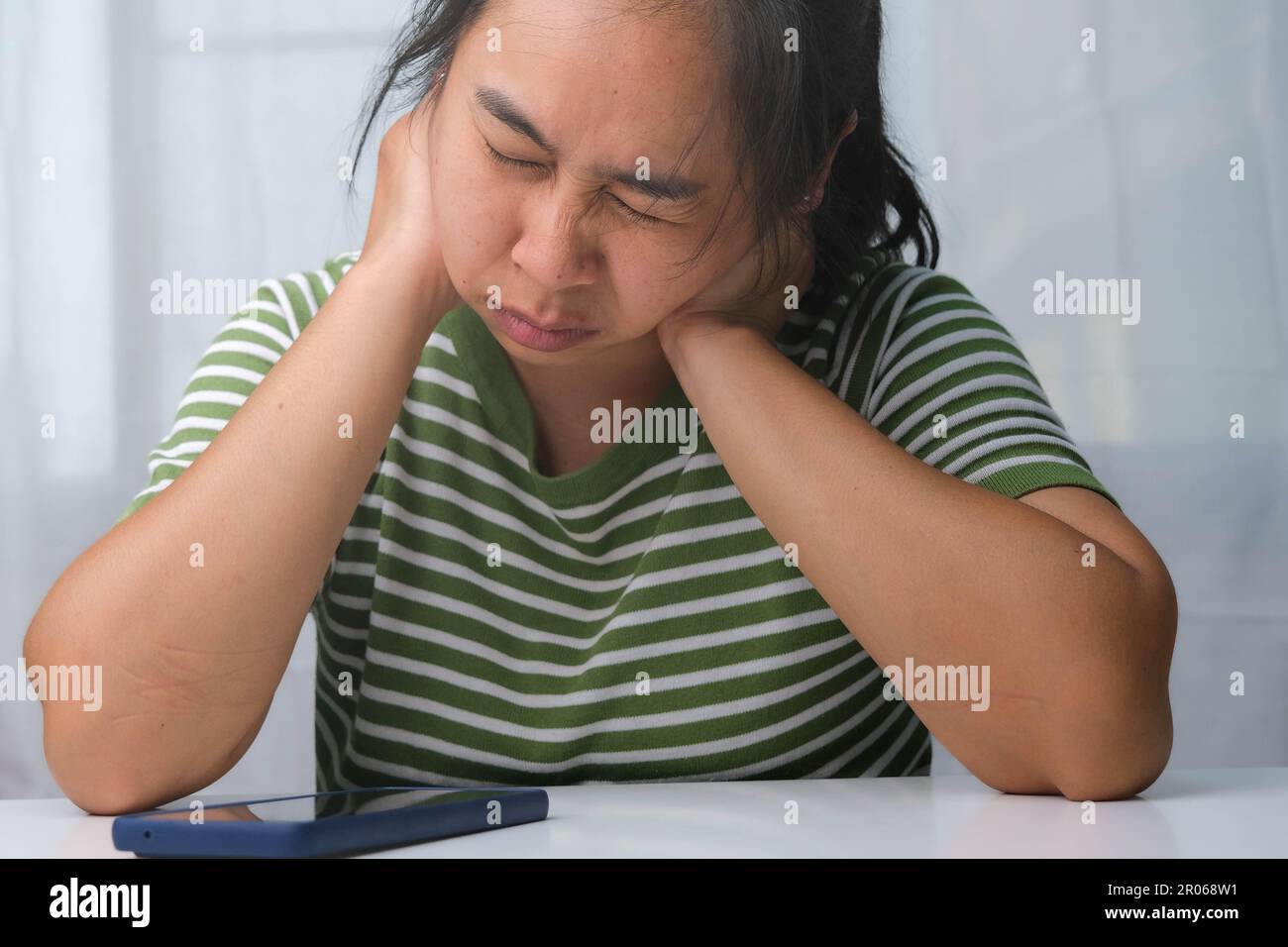 Moody giovane donna che tiene il collo. Donna stanca massaggiando il collo rigido, sforzando i muscoli, esausta dal lavoro. Dolore alla parte superiore del braccio. Sanità e medicina Foto Stock