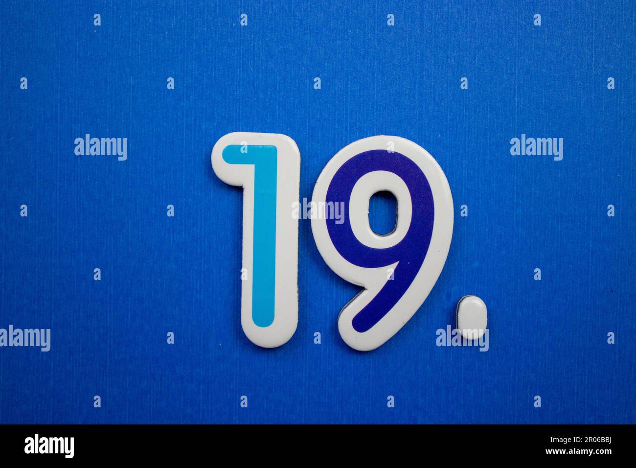 Il numero 19 in colori blu chiaro e scuro, posto su uno sfondo blu, fotografato dall'alto. Foto Stock